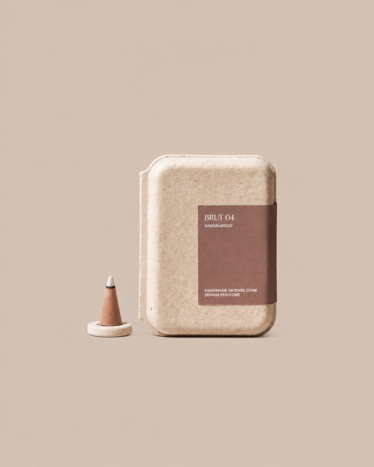 BRUT 04 handmade sandalwood incense cone box beside a cone on the included holder, on a clean beige background.