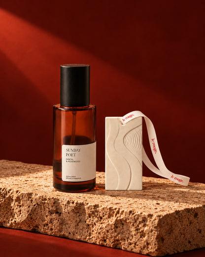 Sunday Poet room spray and WAVE ornament duo styled on stone with a red backdrop