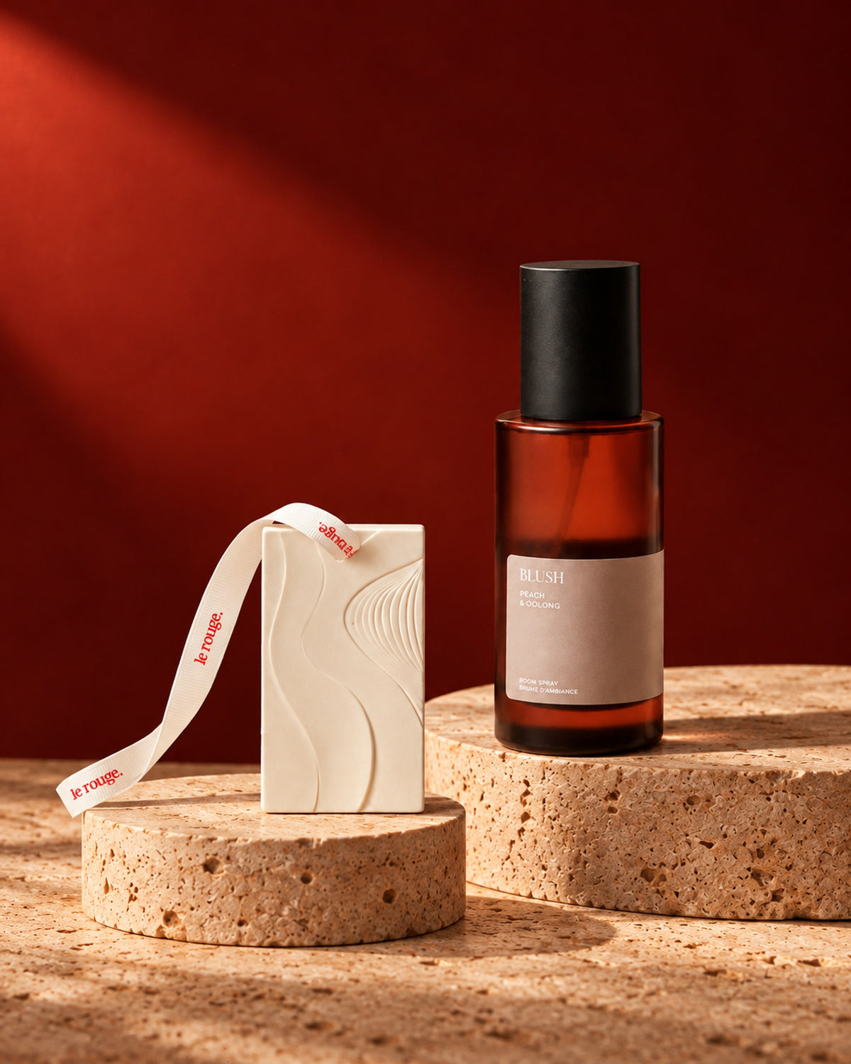Blush room spray and WAVE ornament duo styled on stone with a red backdrop