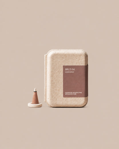 BRUT 04 handmade sandalwood incense cone box beside a cone on the included holder, on a clean beige background.